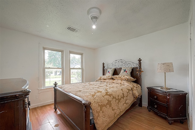 bedroom with light hardwood / wood-style flooring and a textured ceiling