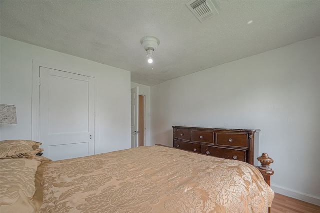 bedroom with wood-type flooring and a textured ceiling