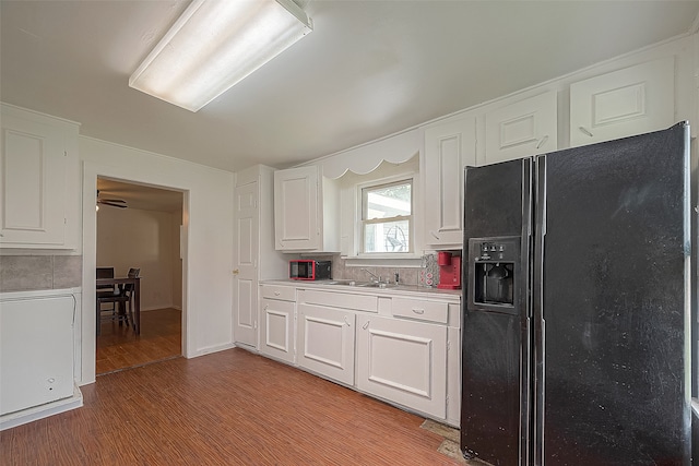 kitchen with backsplash, light hardwood / wood-style flooring, white cabinets, and black refrigerator with ice dispenser