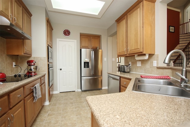 kitchen with light stone counters, light tile floors, sink, backsplash, and stainless steel appliances