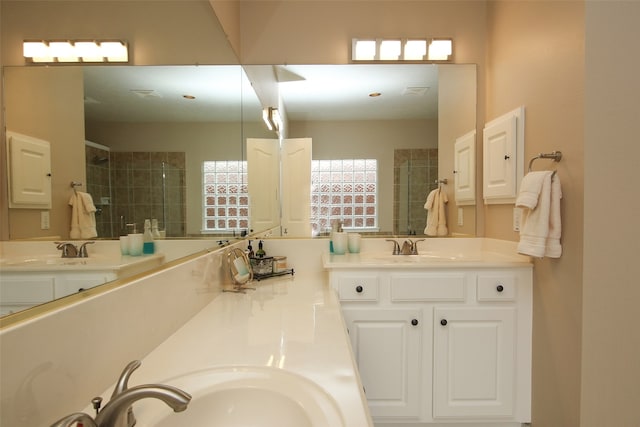 bathroom with tiled shower and double vanity