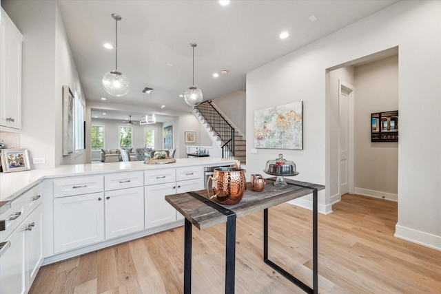 kitchen featuring light wood-style floors, pendant lighting, light countertops, and white cabinetry