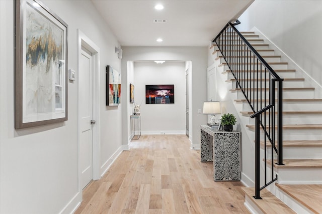 hall with visible vents, baseboards, light wood-style flooring, stairway, and recessed lighting