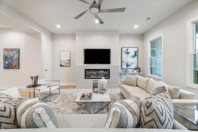 living area with visible vents, a glass covered fireplace, ceiling fan, light wood-style floors, and recessed lighting