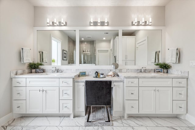 full bathroom featuring marble finish floor, two vanities, a sink, and baseboards