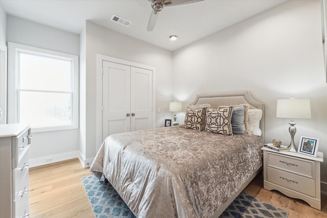 bedroom with a closet, visible vents, a ceiling fan, light wood-type flooring, and baseboards