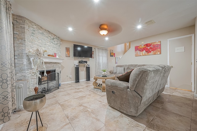 living room featuring a fireplace, ceiling fan, and light tile floors