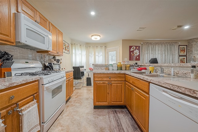 kitchen featuring white appliances, sink, and light tile flooring