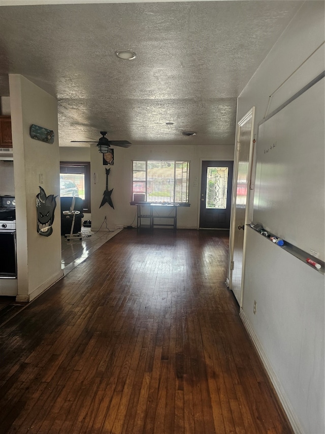 hallway featuring a textured ceiling, a healthy amount of sunlight, and dark wood-type flooring