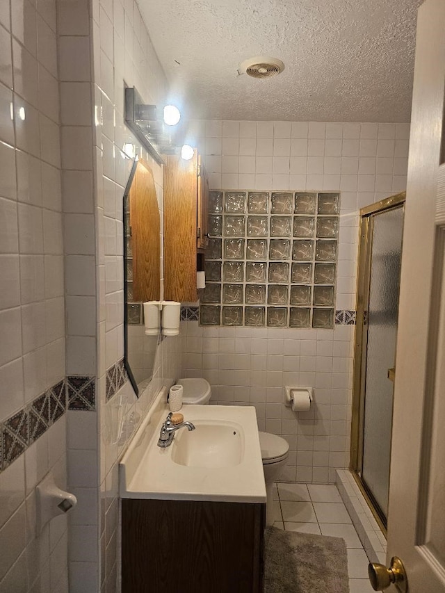 bathroom with toilet, tile walls, vanity, and tile floors