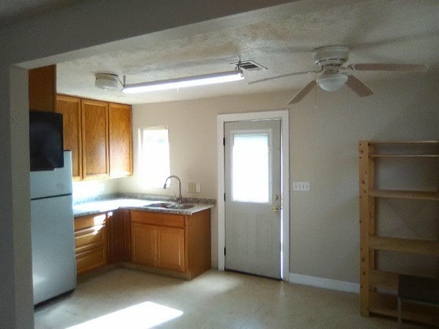 kitchen featuring a textured ceiling, ceiling fan, white refrigerator, and sink