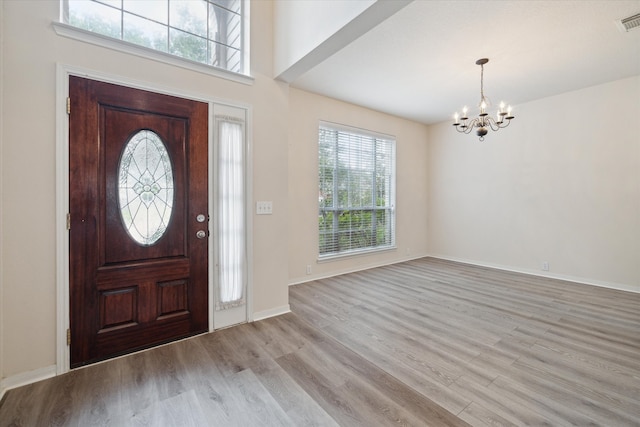 foyer entrance with light hardwood / wood-style flooring, an inviting chandelier, and a high ceiling