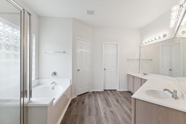 bathroom with wood-type flooring, a washtub, and dual bowl vanity