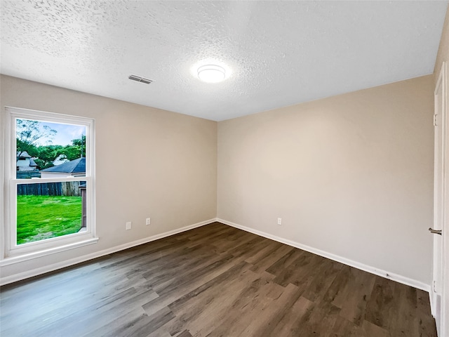 spare room with dark hardwood / wood-style floors and a textured ceiling