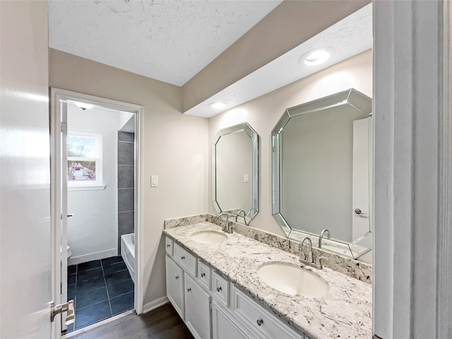 bathroom with oversized vanity, shower / bath combination, tile flooring, a textured ceiling, and double sink