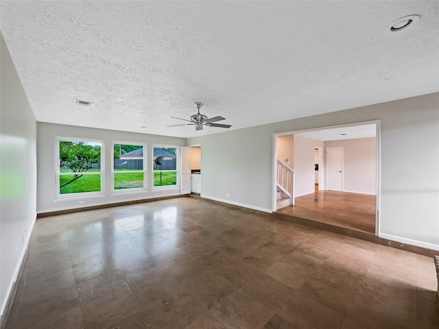 tiled empty room with ceiling fan and a textured ceiling