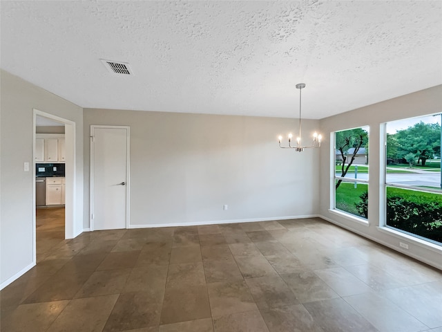 tiled empty room featuring a notable chandelier and a textured ceiling