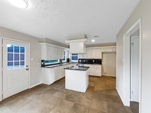 kitchen featuring a kitchen island, tile flooring, white cabinetry, and a textured ceiling