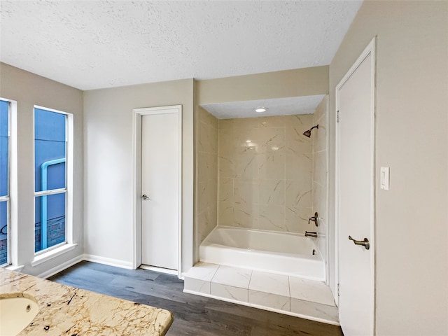 bathroom featuring hardwood / wood-style flooring, tiled shower / bath combo, vanity, and a textured ceiling