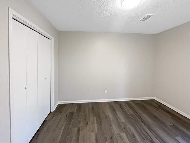 unfurnished bedroom featuring dark hardwood / wood-style flooring, a closet, and a textured ceiling