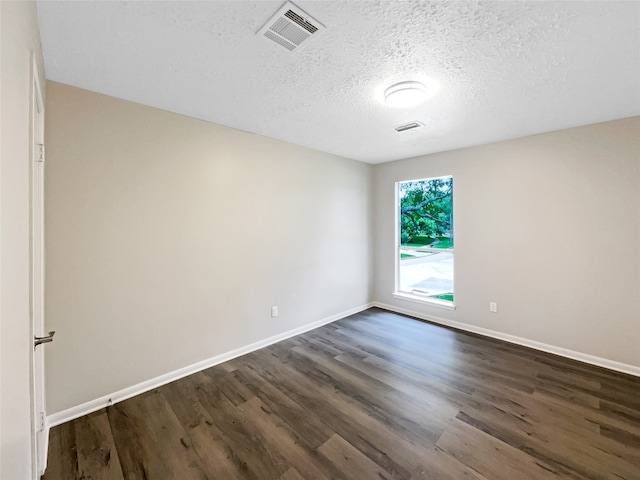 empty room with a textured ceiling and dark wood-type flooring