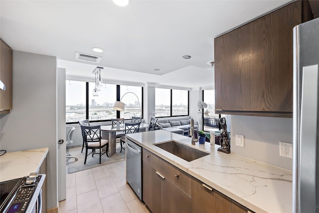 kitchen with a healthy amount of sunlight, stainless steel appliances, sink, and light tile flooring