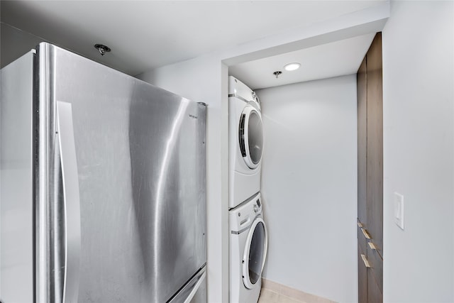 laundry area with light tile flooring and stacked washer / drying machine