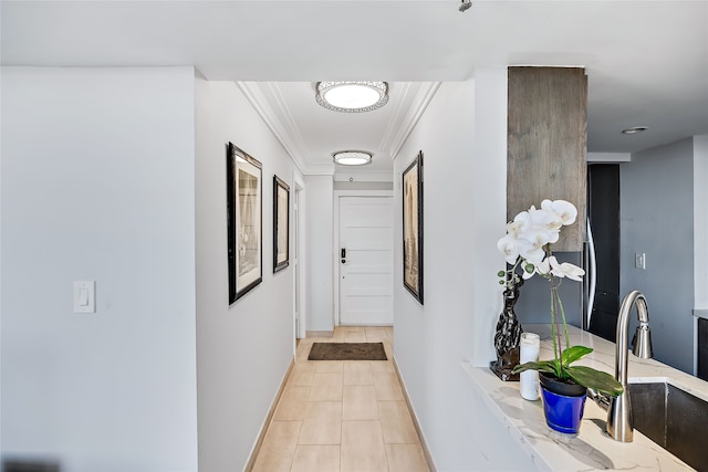 hall featuring sink, crown molding, and light tile floors