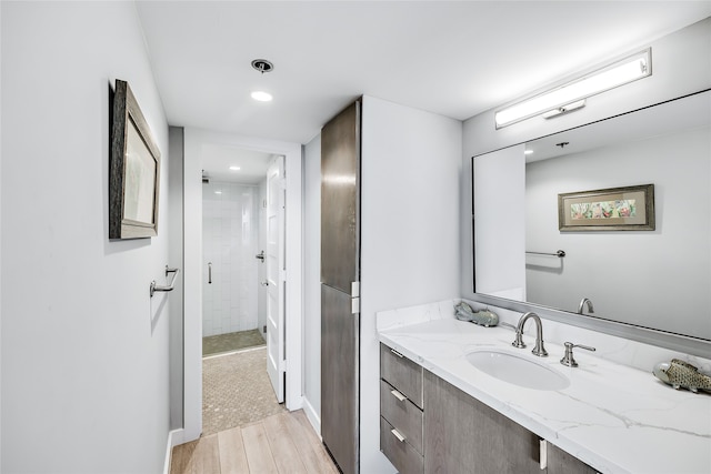 bathroom with a shower with shower door, wood-type flooring, and oversized vanity