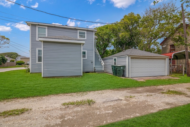 rear view of property with a garage, a carport, a yard, and an outdoor structure