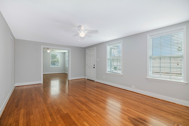 empty room featuring a healthy amount of sunlight, ceiling fan, and hardwood / wood-style floors