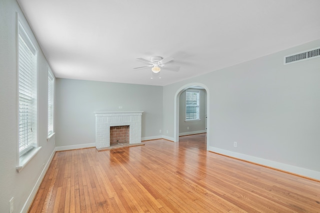 unfurnished living room featuring light hardwood / wood-style flooring, a healthy amount of sunlight, ceiling fan, and a fireplace