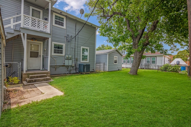 rear view of property with a yard, a balcony, and central AC unit