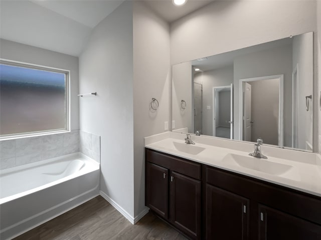 bathroom with lofted ceiling, a bathtub, hardwood / wood-style flooring, and double sink vanity