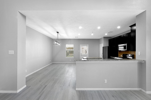 kitchen with hanging light fixtures, kitchen peninsula, light wood-type flooring, and stove