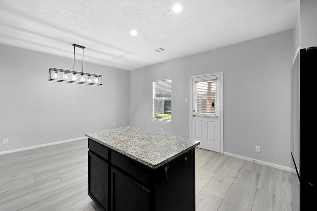 kitchen with a kitchen island, light hardwood / wood-style flooring, a textured ceiling, and hanging light fixtures