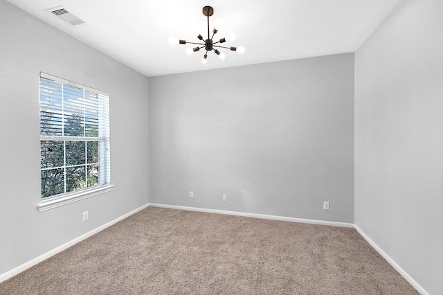 carpeted spare room featuring a notable chandelier