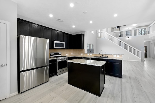 kitchen featuring light stone counters, a center island, tasteful backsplash, stainless steel appliances, and kitchen peninsula