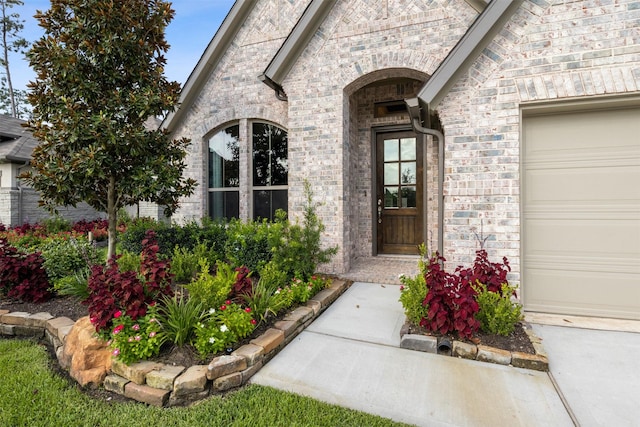 doorway to property featuring a garage and brick siding