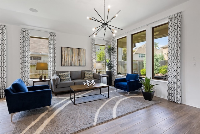 living room with baseboards, wood finish floors, and an inviting chandelier