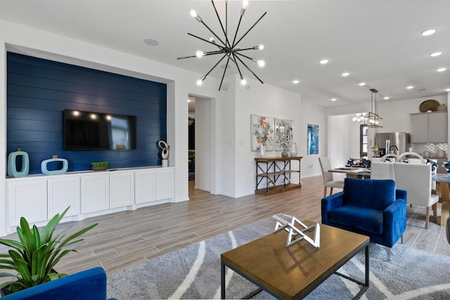 living room featuring an inviting chandelier, baseboards, light wood-style floors, and recessed lighting