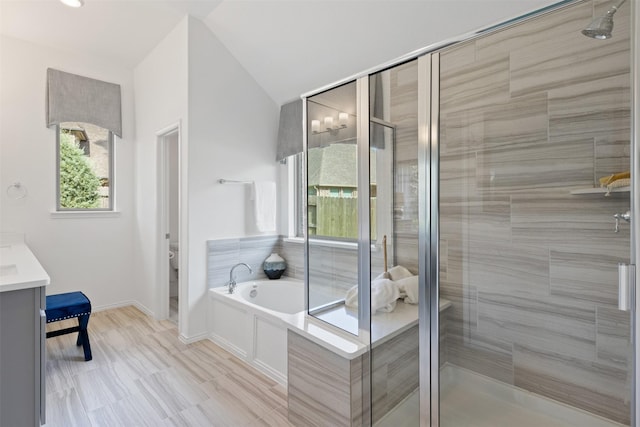 bathroom featuring toilet, vaulted ceiling, vanity, a shower stall, and a bath