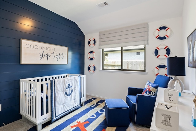 carpeted bedroom featuring a nursery area, lofted ceiling, visible vents, and baseboards