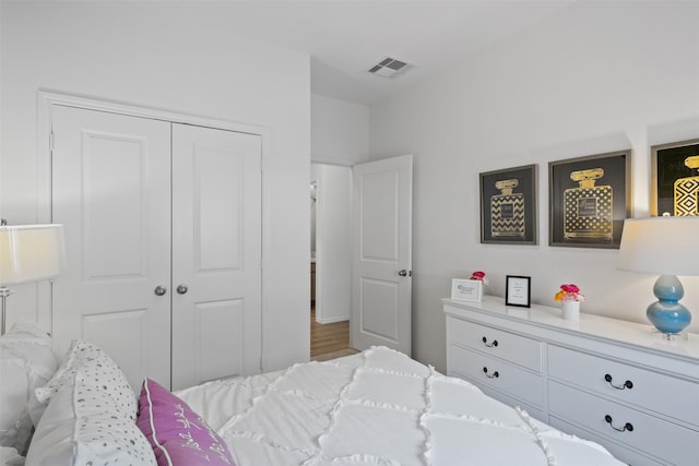 bedroom featuring visible vents, a closet, and wood finished floors