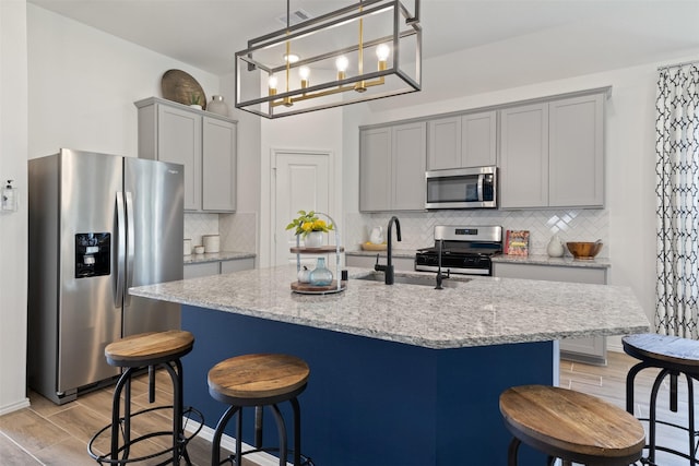 kitchen featuring stainless steel appliances, wood tiled floor, a sink, and gray cabinetry