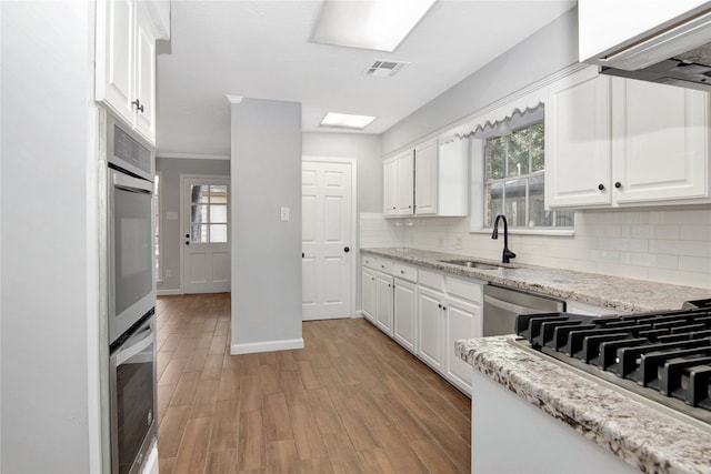 427 Pebblebrook Dr, El Lago, TX 77586 - kitchen featuring white cabinets, sink, tasteful backsplash, and light wood-type flooring