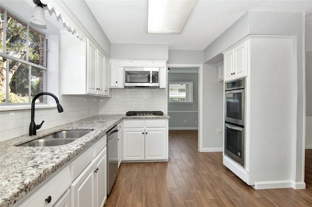 427 Pebblebrook Dr, El Lago, TX 77586 - kitchen featuring backsplash, hardwood / wood-style floors, white cabinetry, light stone countertops, and appliances with stainless steel finishes