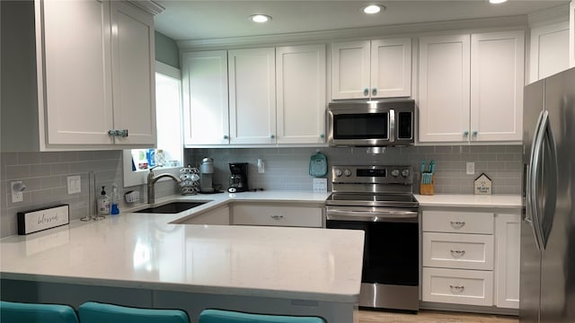 kitchen with a kitchen bar, sink, tasteful backsplash, and stainless steel appliances