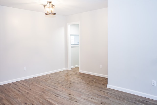 unfurnished room with wood-type flooring and a chandelier