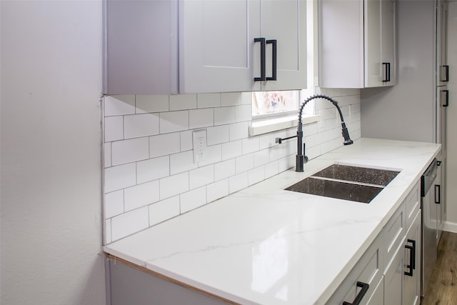 kitchen featuring wood-type flooring, dishwasher, backsplash, and sink